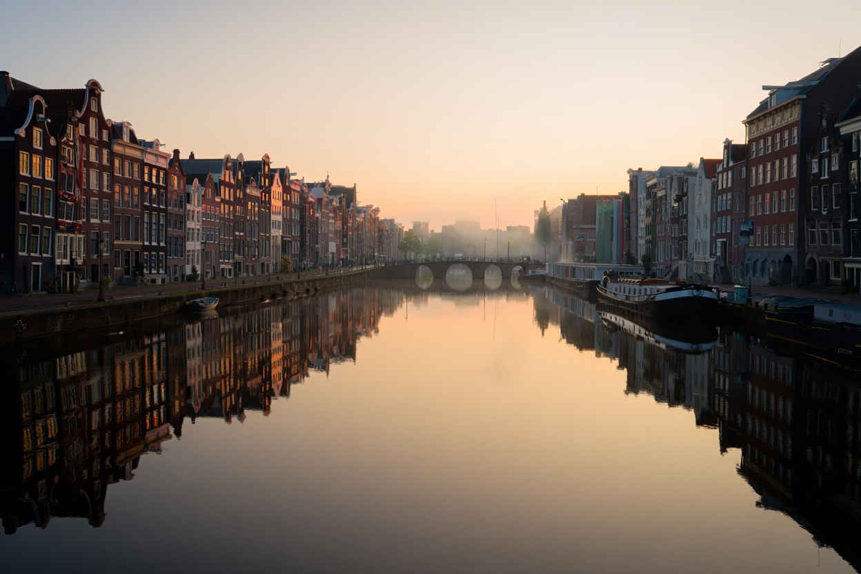 Vroege ochtend op de Amsterdamse grachten met reflecties van grachtenpanden in het stille water