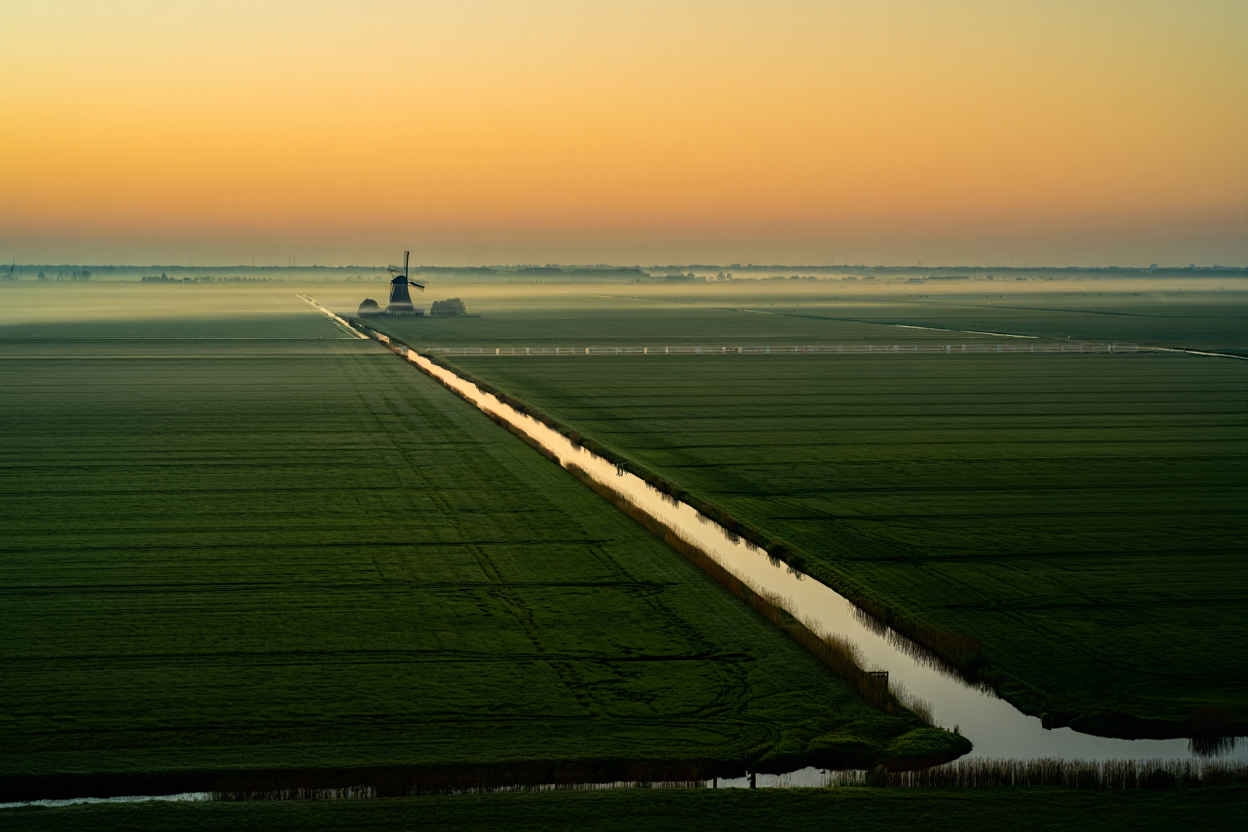Panoramisch uitzicht over de Nederlandse kanalen en weilanden bij zonsopgang